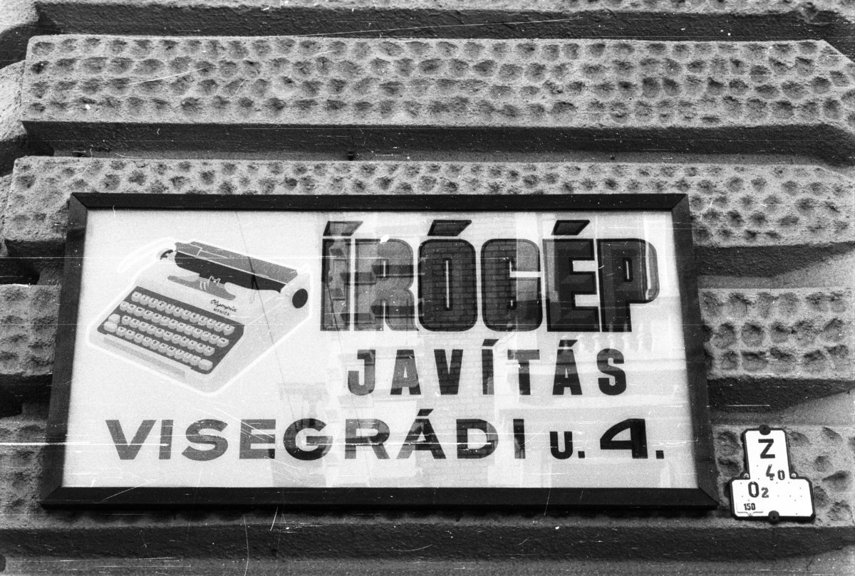Framed advertisement for a typewriter repair service in Budapest, on the wall of a house